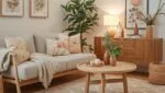 Sala de estar aconchegante e organizada com sofá claro com estrutura de madeira, almofadas com estampas florais suaves e tons de bege e pêssego.
